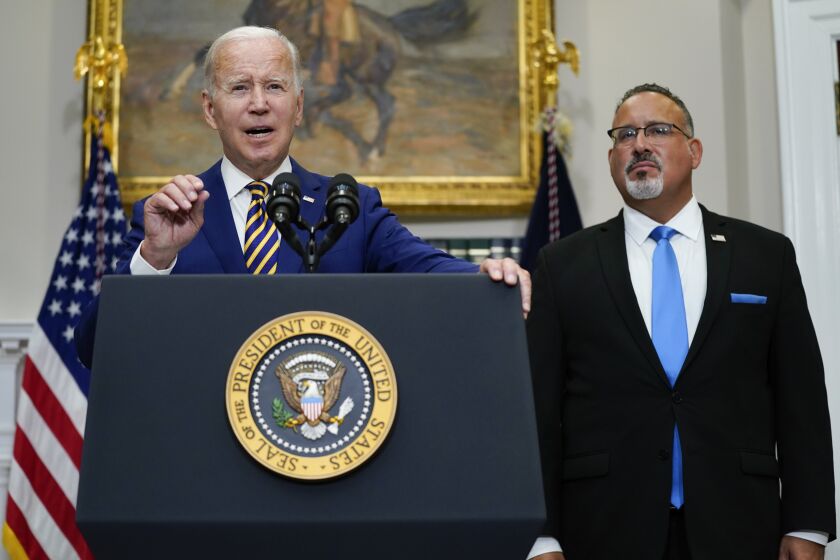 President Joe Biden speaks about student loan debt forgiveness in the Roosevelt Room of the White House, Wednesday, Aug. 24, 2022, in Washington. Education Secretary Miguel Cardona listens at right. (AP Photo/Evan Vucci)