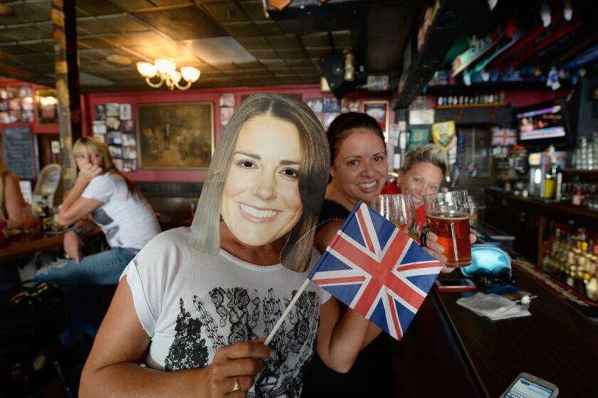 Karen Milne, left, from Scotland, wears a mask of Catherine, the Duchess of Cambridge, as she celebrates the royal birth with friends Rachelle Rodriguez, center, and Michelle Lewis, right, at Ye Olde King's Head British Pub in Santa Monica.