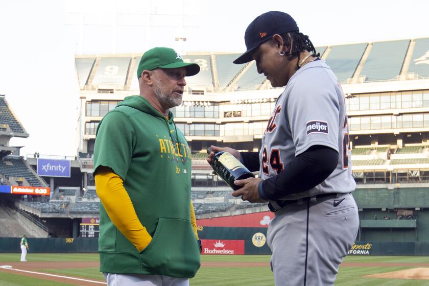 Oakland Athletics manager Mark Kotsay presents a bottle of wine to Detroit Tigers designated hitter Miguel Cabrera