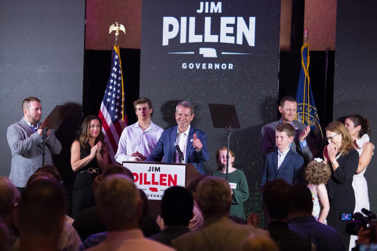 Nebraska gubernatorial candidate at lectern with supporters