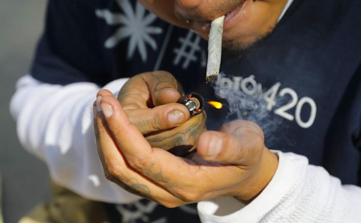 Un hombre enciende un cigarrillo de marihuana