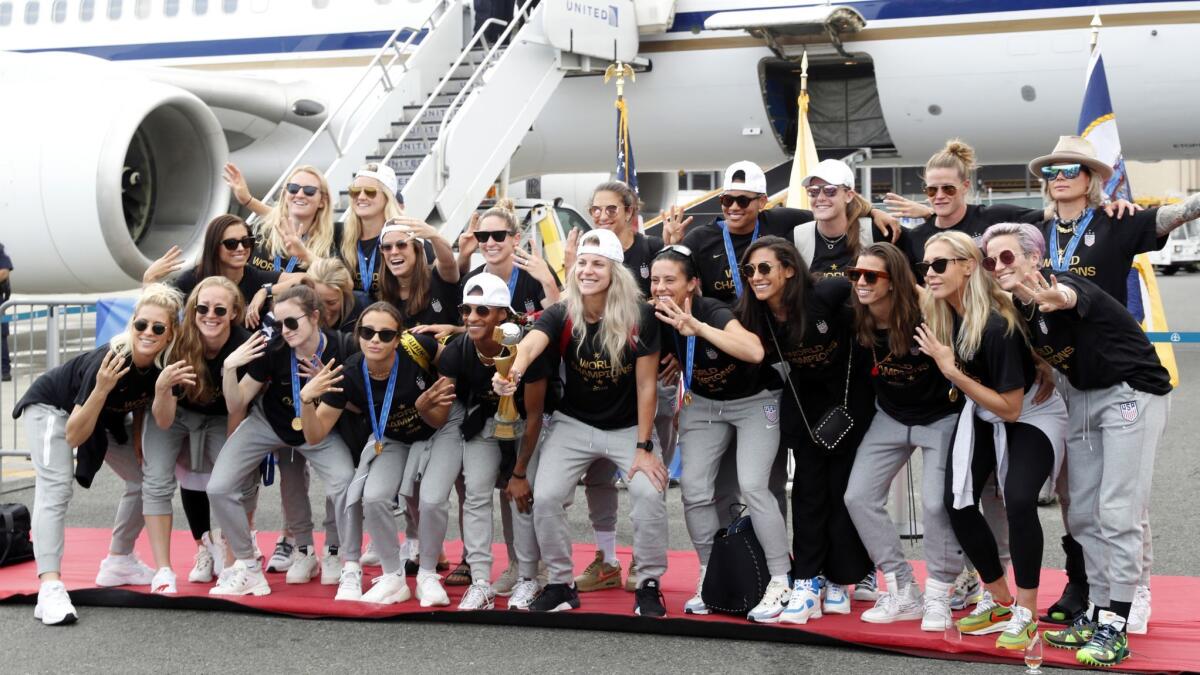 Members of the U.S. women's soccer team pose with the World Cup trophy Monday after arriving at Newark Liberty International Airport in New Jersey.