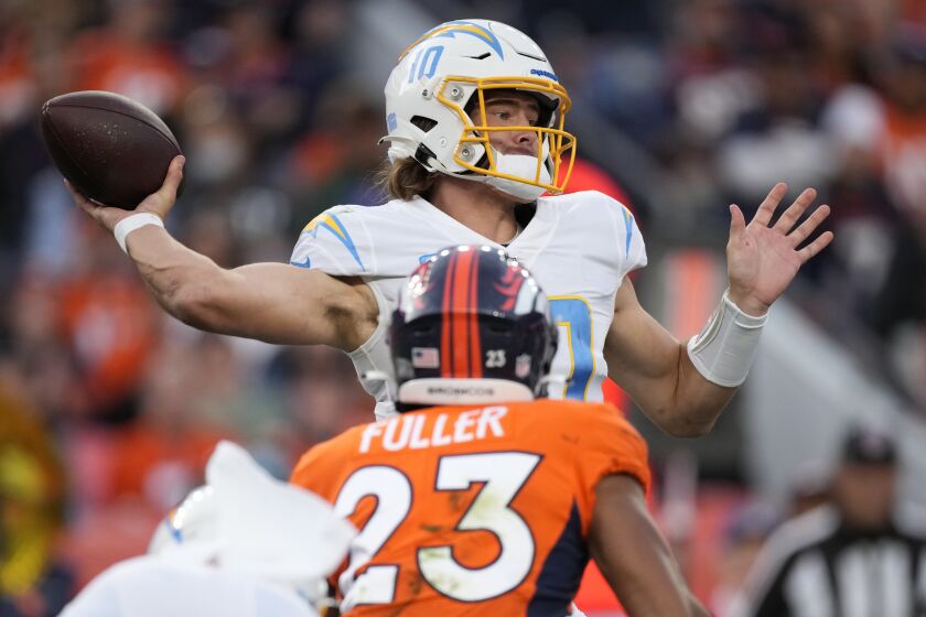 Los Angeles Chargers quarterback Justin Herbert (10) throws as Denver Broncos cornerback Kyle Fuller (23) pursues during the second half of an NFL football game, Sunday, Nov. 28, 2021, in Denver. (AP Photo/David Zalubowski)