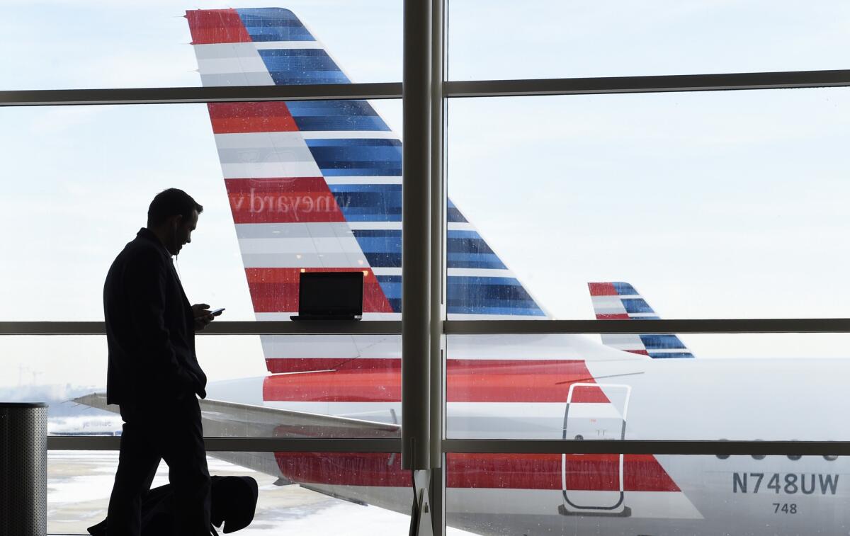 A traveler talks on the phone as American Airlines jets sit parked at Washington's Ronald Reagan National Airport in 2016.