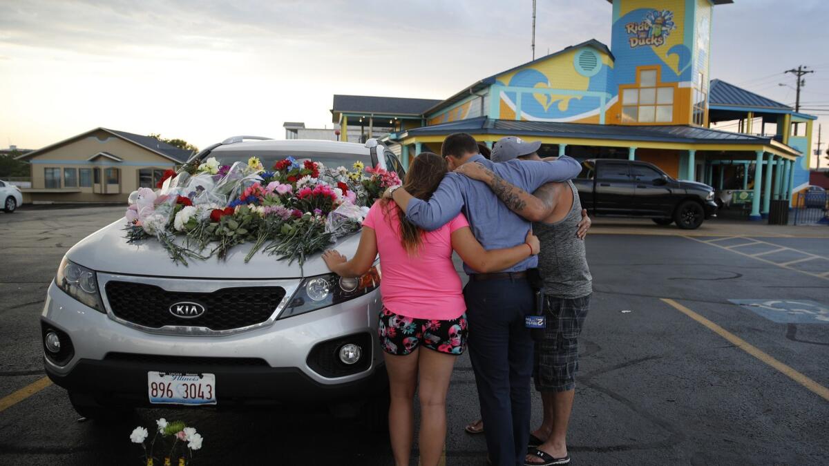 People pray by a victim's car Friday in the parking lot of Ride the Ducks in Branson, Mo.