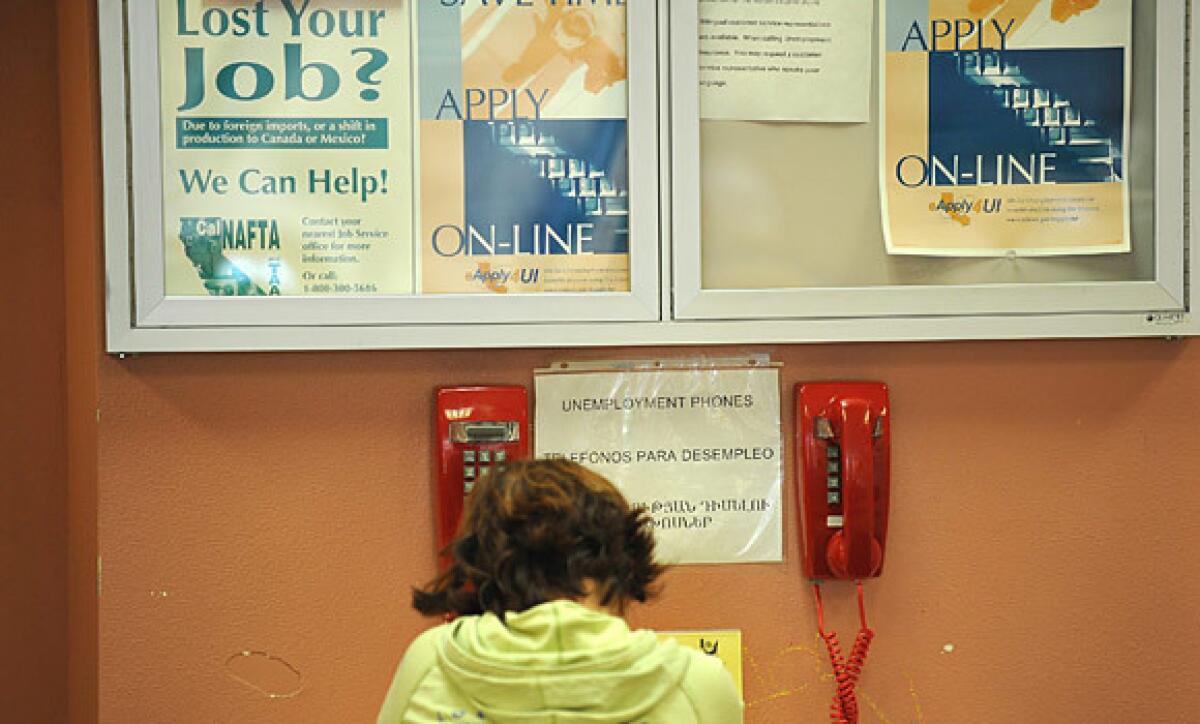 A woman uses a telephone at a job center in Glendale to apply for unemployment benefits.