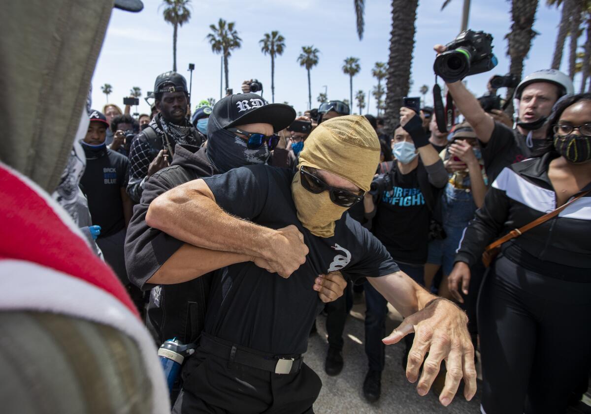 Protesters scuffle during a rally against racial injustice and police brutality at the Huntington Beach Pier on Sunday.