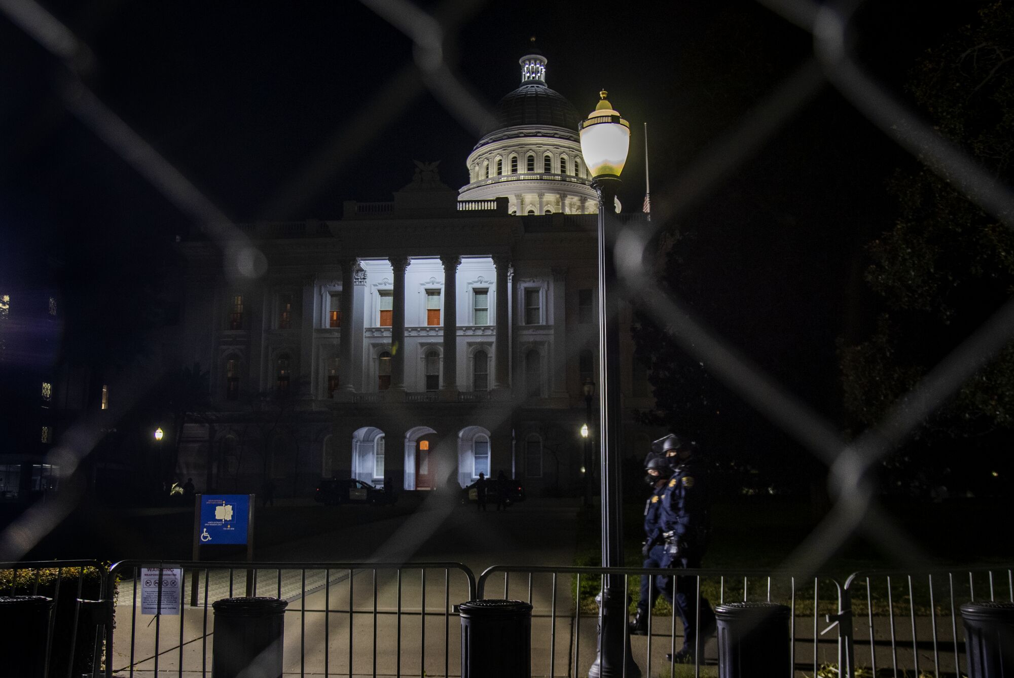 The California State Capitol dome is lit while CHP officers patrol the grounds in anticipation of possible unrest.