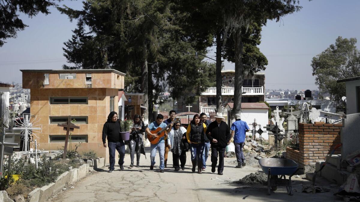 NICOLAS ROMERO, MEXICO - FEBRUARY 10, 2019: The family of Eduardo Hernandez walks through the cemetery to visit his grave on the one year anniversary of his death. Eduardo Hernandez, a 60-year-old day laborer from Mexico, was dying of colon cancer at a hospital in Pasadena. He had no family in the U.S., where he had spent half his life, and his only visitors were other day laborers. A week before he died, the director of the labor center was able to contact his estranged wife and sons, who he hadn?t seen in 10 years since the last time he crossed illegally into California. (Katie Falkenberg / Los Angeles Times)