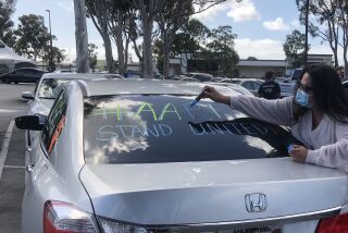 Roseanna Rosette, of Filipino and Mexican descent, writes a message on a car before a caravan of cars rallied against anti-Asian hate and in support of the Black Lives Matter movement.