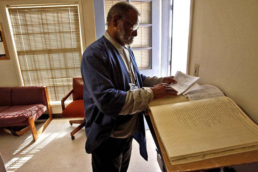 Albert Gaskin stands over a ledger in which he maintains a list of individuals who've been cremated at the county crematory. The book contains 1,000 pages, many filled with names of people whose ashes remain unclaimed.