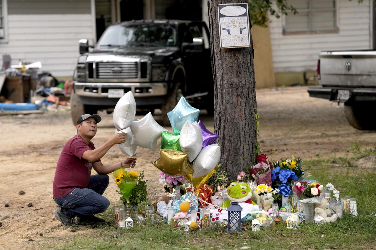 A man releases a balloon from a memorial outside a home.