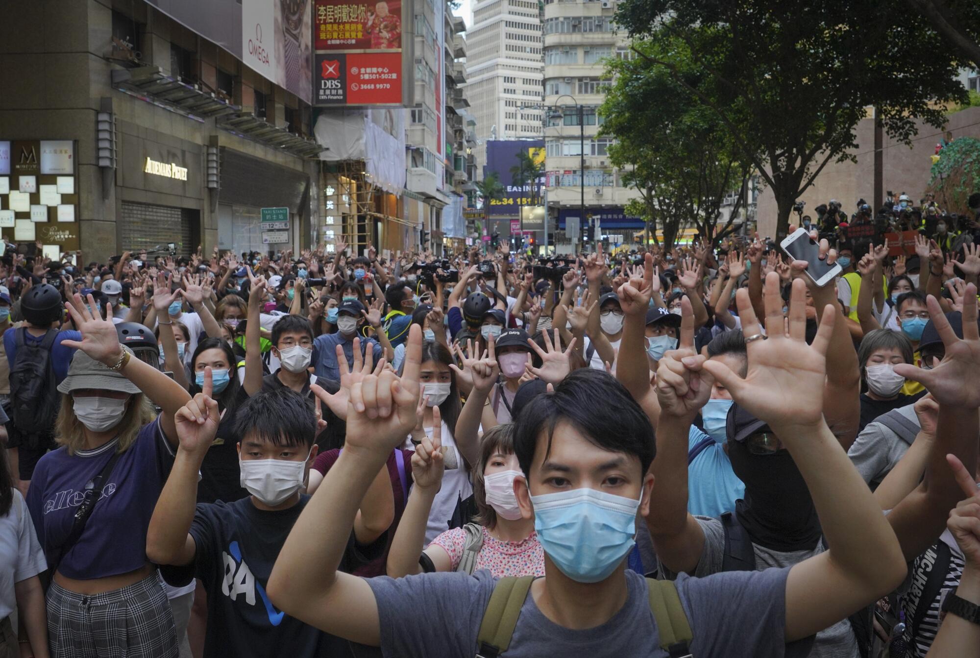 Protesters against Hong Kong's new national security law gesture with five fingers.