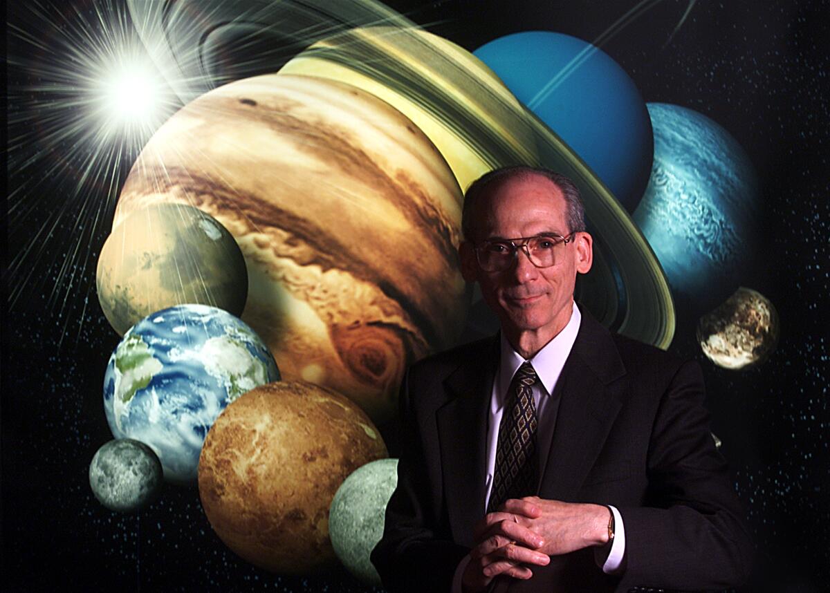 Portrait of Ed Stone, wearing a suit, with a background showing planets 