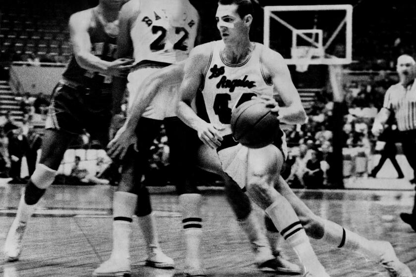 WAY OF THE WEST: Lakers?€? Jerry West, a piece of tape "protecting" his broken nose, heads for bucket as Elgin Baylor screens out unidentified Knickerbocker in game Wednesday night at Sports Area. PHOTOGRAPHER: Larry Sharkey / Los Angeles Times DATE PUBLISHED IN LA Times: January 21, 1965