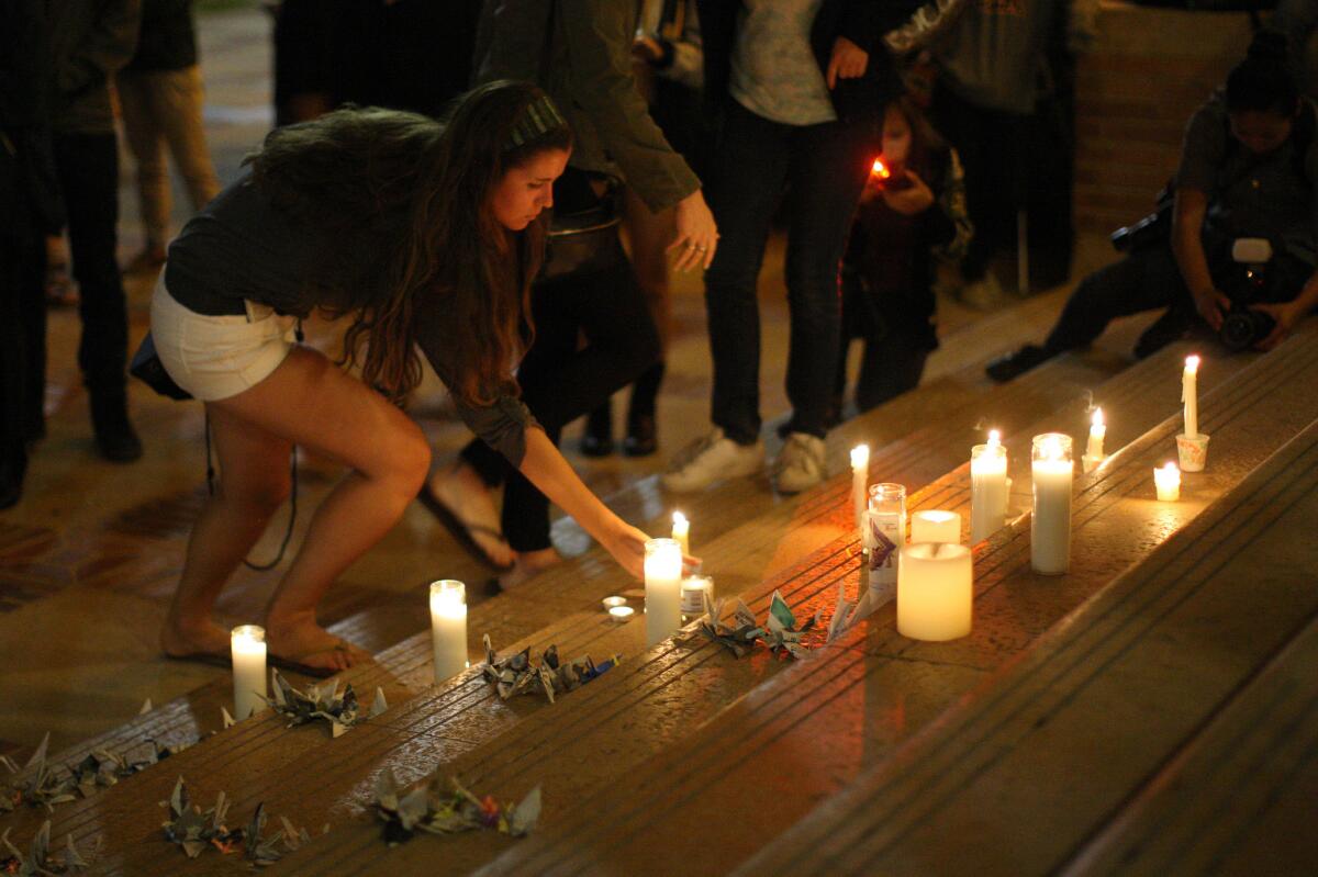A student places a candle as students of UCSB and UCLA mourn at a candlelight vigil at UCLA for the victims of a killing rampage over near UCSB.