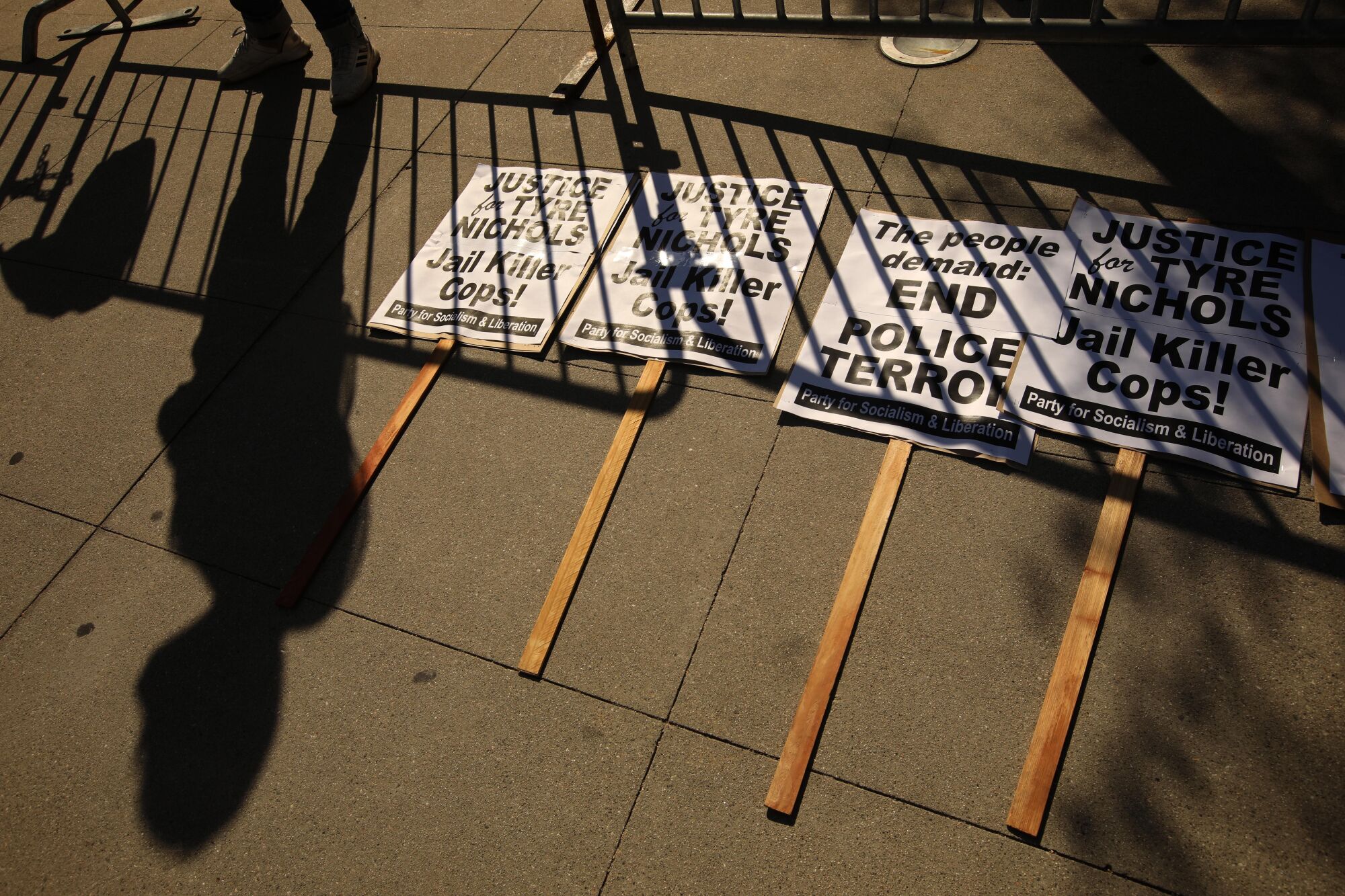 A shadow is cast over picket signs, some with writing "end police terror. jail killer cops."