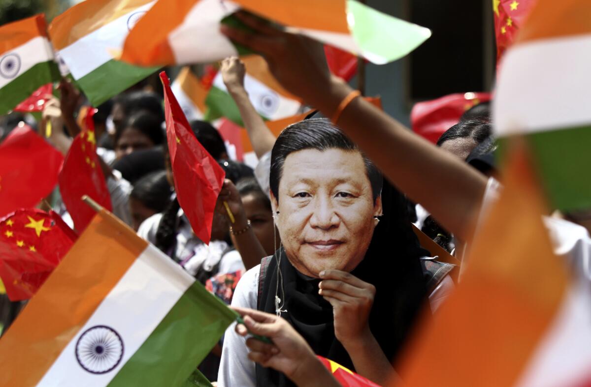 FILE- An Indian schoolgirl wears a mask of Chinese President Xi Jinping to welcome him on the eve of his visit in Chennai, India, Oct. 10, 2019. Indian and Chinese soldiers began pulling back from one of the key friction points on their disputed border on Thursday, Sept. 8, 2022, as part of efforts to lower tensions in a more than two-year standoff that has sometimes led to deadly clashes, India’s defense ministry said. The disengagement followed a 16th round of commander-level talks between the two countries in July, it said. (AP Photo/R. Parthibhan, File)