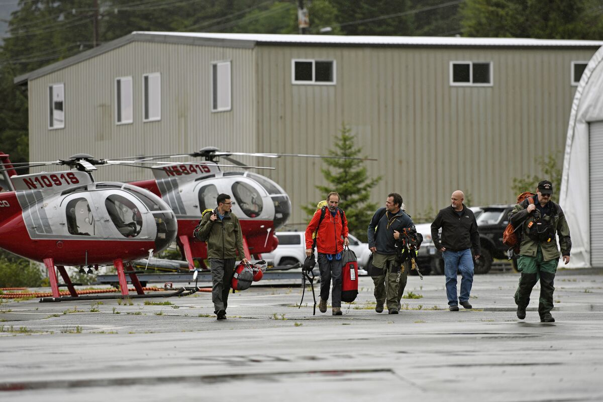 Ketchikan Volunteer Rescue Squad personnel land and disembark from a Hughes 369D helicopter on Thursday, Aug. 5, 2021, at Temsco Helicopters Inc in Ketchikan, Alaska. The KVRS, U.S. Coast Guard, Alaska State Troopers and U.S. Forest Service responded to a radio beacon alert from a downed Southeast Aviation de Havilland Beaver float plane that was carrying five passengers from the Holland America Line cruise ship Nieuw Amsterdam, according to Coast Guard, Holland America and KVRS information. The sightseeing plane crashed Thursday in southeast Alaska, killing all six people on board, the U.S. Coast Guard said. (Dustin Safranek/Ketchikan Daily News via AP)