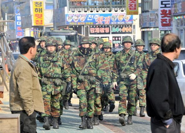 South Korean soldiers march past residents along a coastal road near a beach in the town Taean, southwest of Seoul on November 28, 2010.