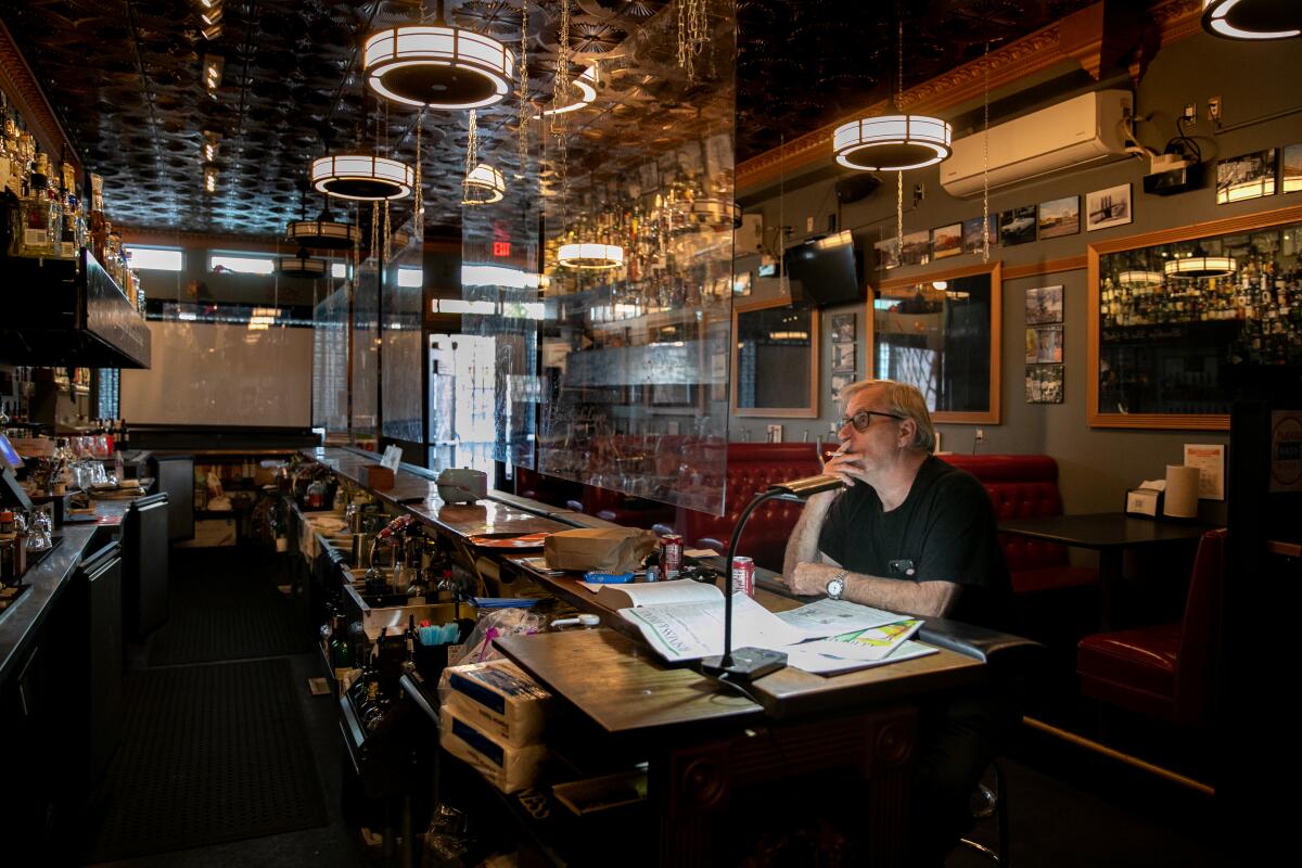 Bill Lutzius, owner of Brooklyn Bar & Grill, smokes a cigarette and watches movies at the bar on Dec. 15.