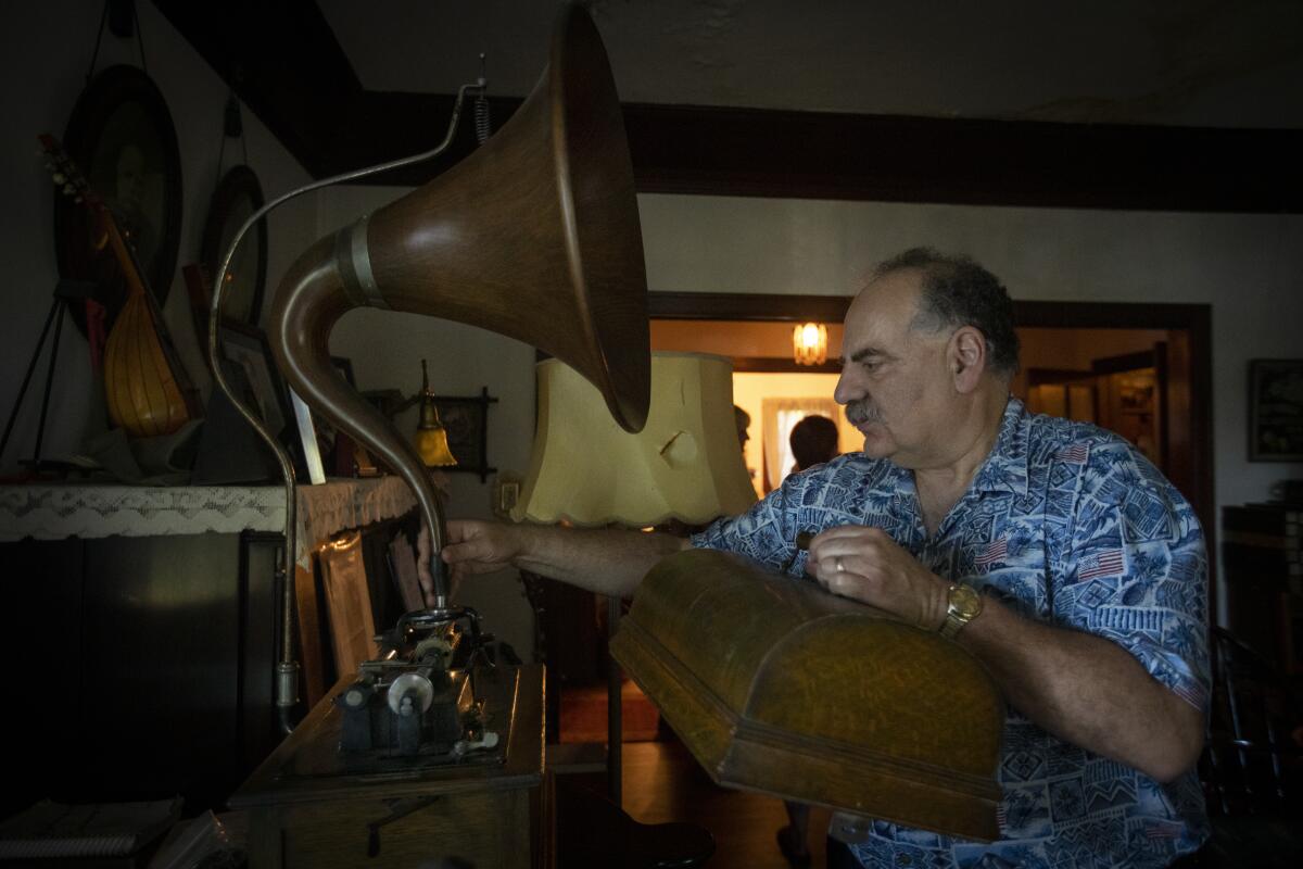 Dr. Michael Khanchalian prepares a 1901 Edison Triumph phonograph with a 1909 cygnet oak horn at his home in Monrovia.