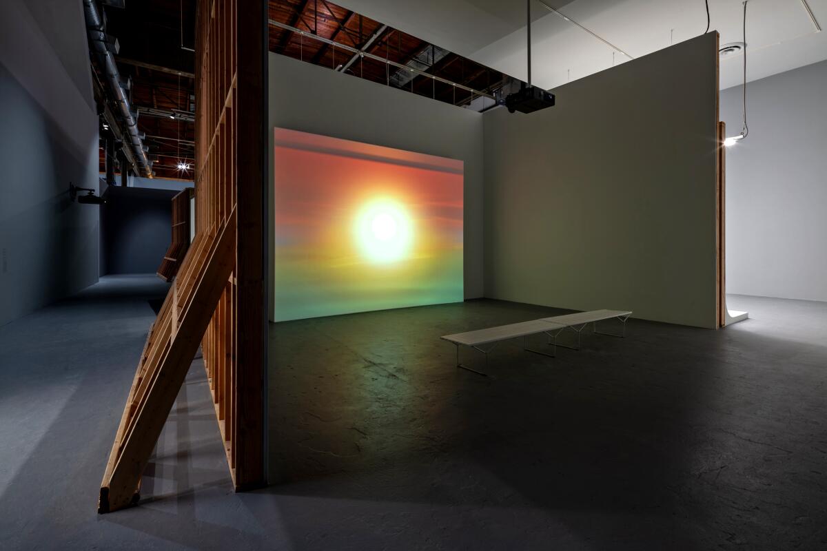 A video installation playing in front of a bench and hidden in a small room