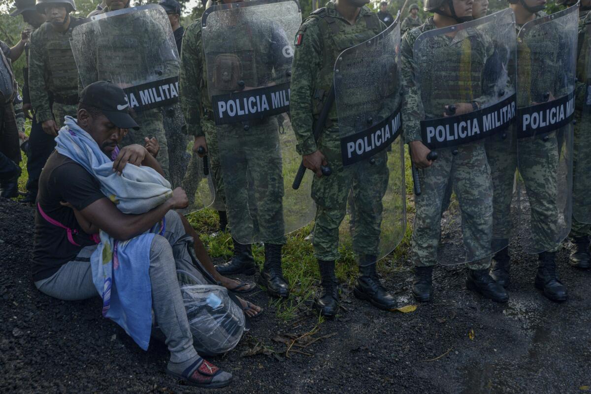 Un migrante atiende a un niño mientras está rodeado por miembros de la Guardia Nacional cerca de Tuzantán, estado de Chiapas, México, el sábado 12 de octubre de 2019. Cientos de migrantes fueron detenidos por las autoridades mexicanas cuando se dirigían a la Ciudad de México.