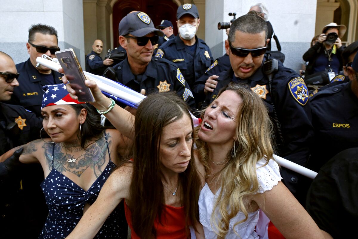 Heidi Munoz Gleisner, left, and Tara Thornton, right, are detained by CHP officers at a rally against stay-at-orders in May.