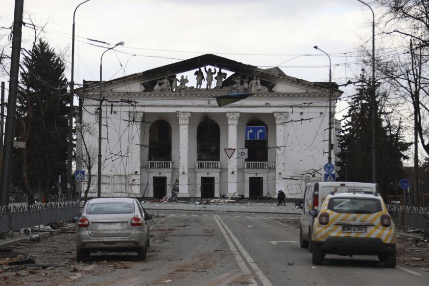 FILE - People walk past the Donetsk Academic Regional Drama Theatre in Mariupol, Ukraine, following a March 16, 2022, bombing of the theater, which was used as a shelter, in an area now controlled by Russian forces on April 4, 2022. Russian troops in Ukraine are deliberately attacking the country's museums, libraries and other cultural institutions, according to a report issued Friday Dec. 2, 2022 by the U.S. and Ukrainian chapters of the international writers' organization PEN. (AP Photo/Alexei Alexandrov, File)