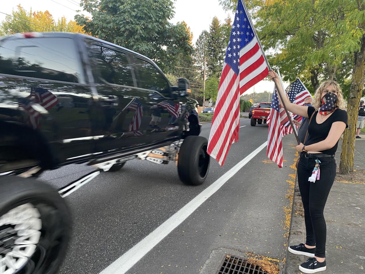 Rebecca Crymer waves a flag at passing cars in Gresham, Ore.