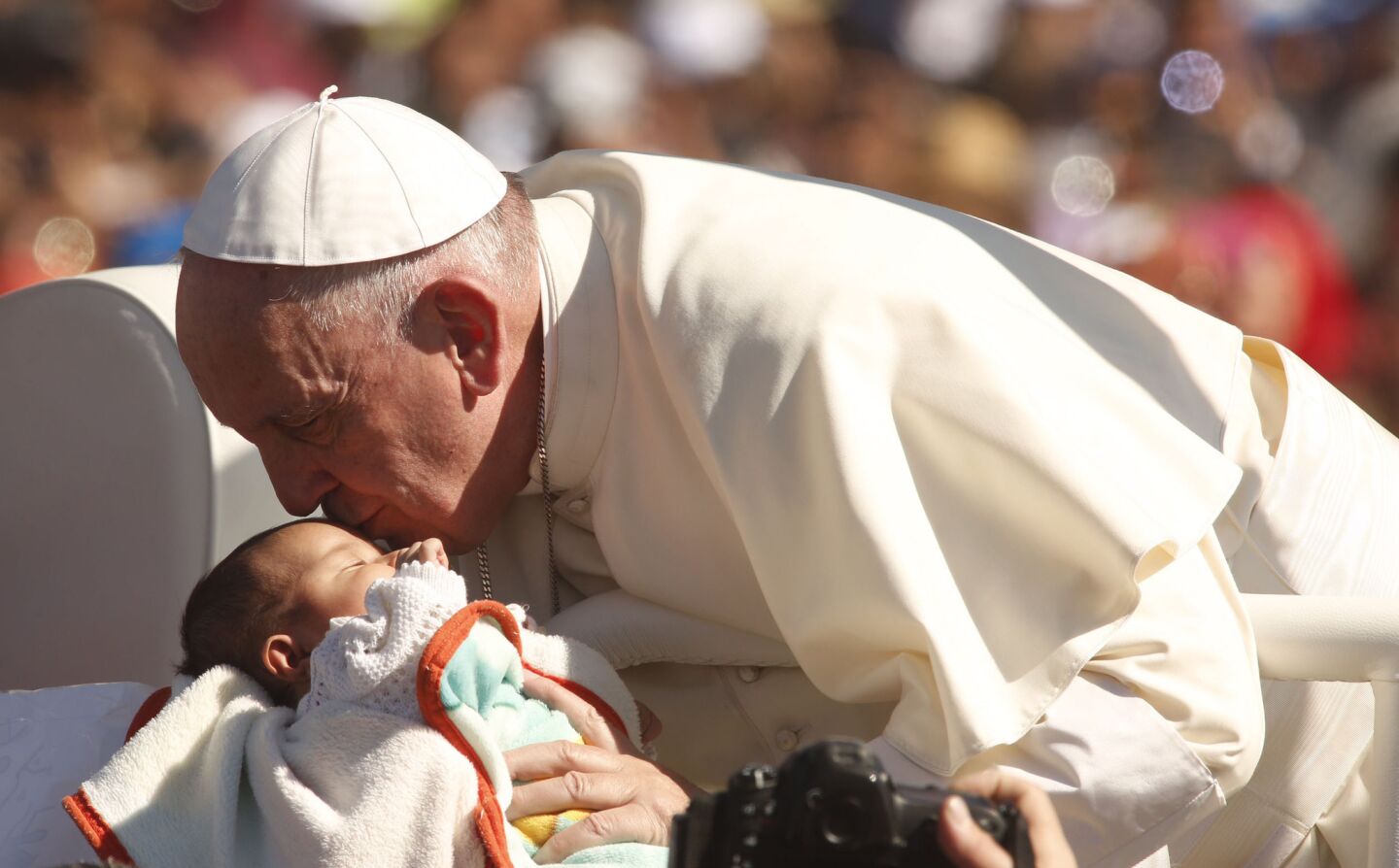 Pope Francis kisses a baby while riding through a crowd of pilgrims, many from indigenous communities surrounding San Cristobal de las Casas. The Mass included several Mayan languages.
