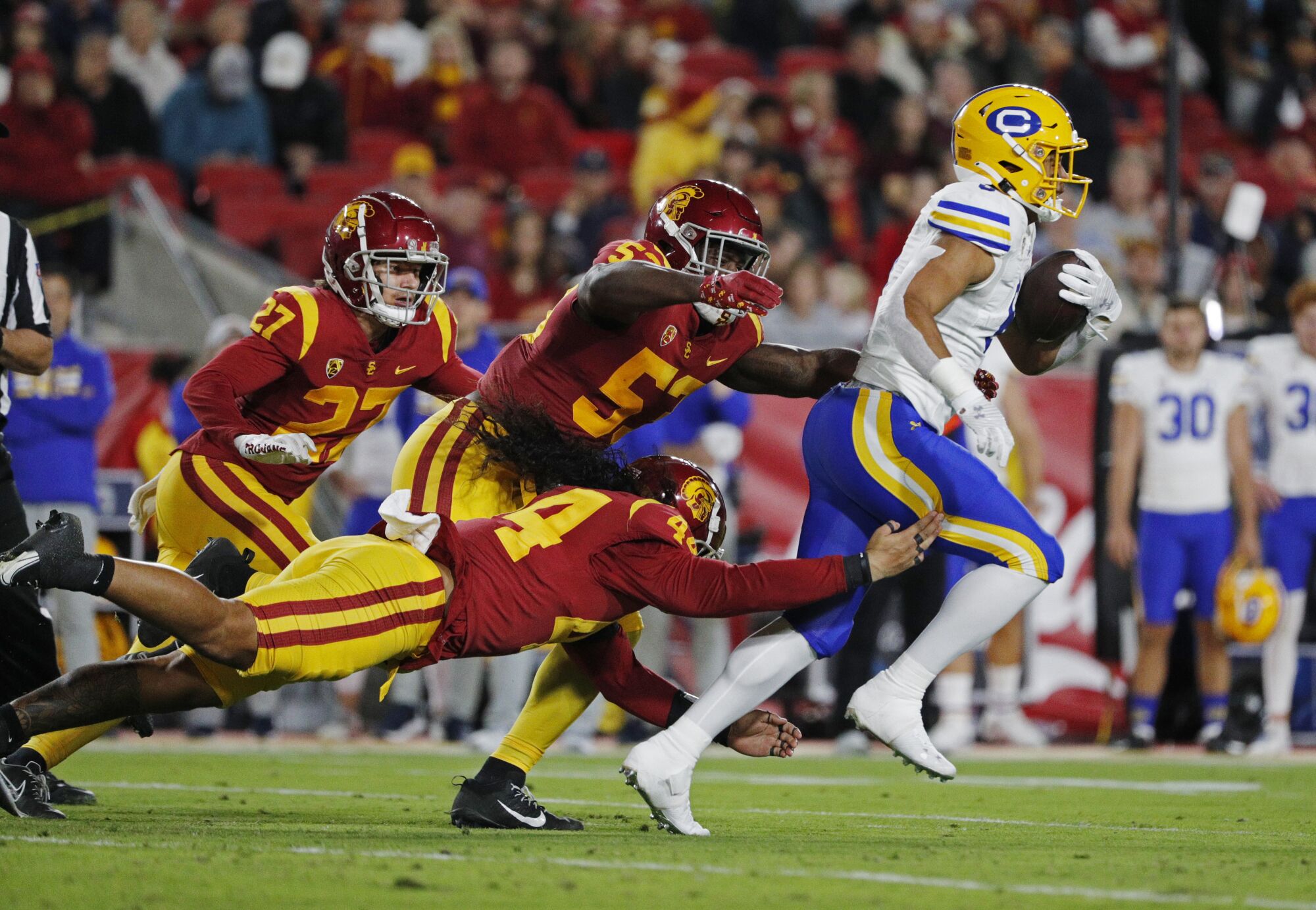 Le porteur de ballon californien Jaydn Ott porte le ballon devant Tuasivi Nomura de l'USC (44), Shane Lee (53) et Bryson Shaw.