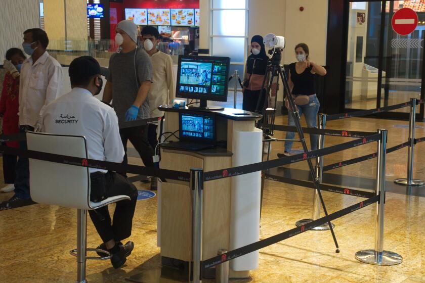 A security guard watches an infrared scanner monitoring incoming customers for fevers at Mall of the Emirates in Dubai, United Arab Emirates, Wednesday, May 27, 2020. Dubai on Wednesday loosed its restrictions imposed over the coronavirus pandemic, allowing movie theaters and other attractions to operate. (AP Photo/Jon Gambrell)
