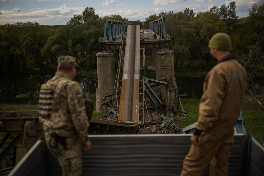 Ukrainian soldiers remove metal structure pieces as they work on a bridge damaged during fighting with Russian troops in Izium, Ukraine, Monday, Oct. 3, 2022. (AP Photo/Francisco Seco)