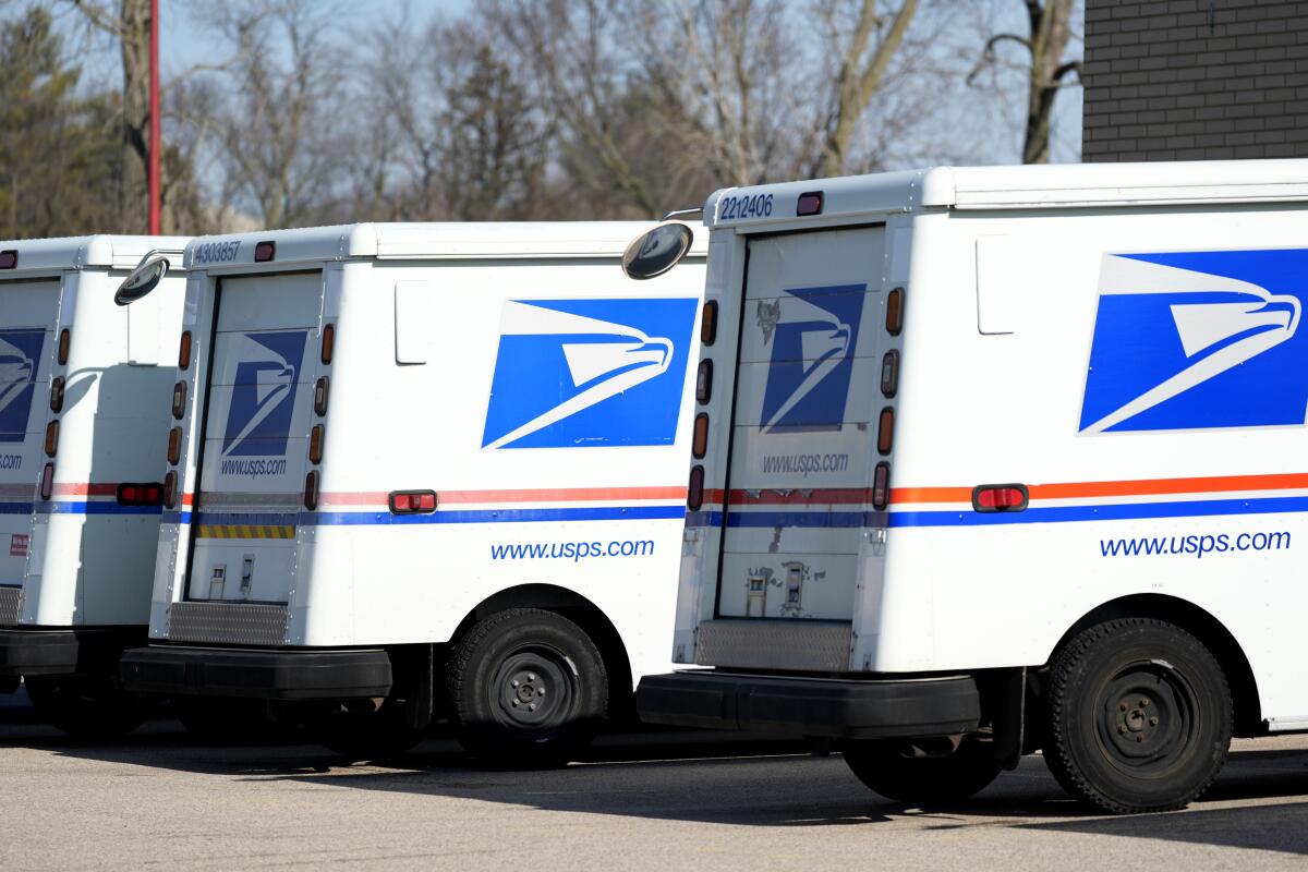 Postal Service trucks parked outside a post office.