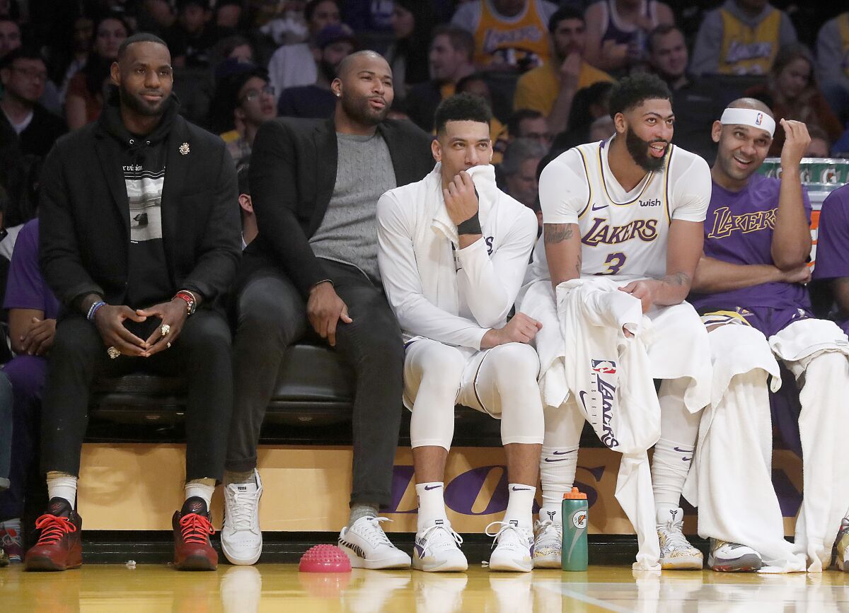 LeBron James, left, watches the Lakers' game against the Denver Nuggets from the bench Sunday at Staples Center.