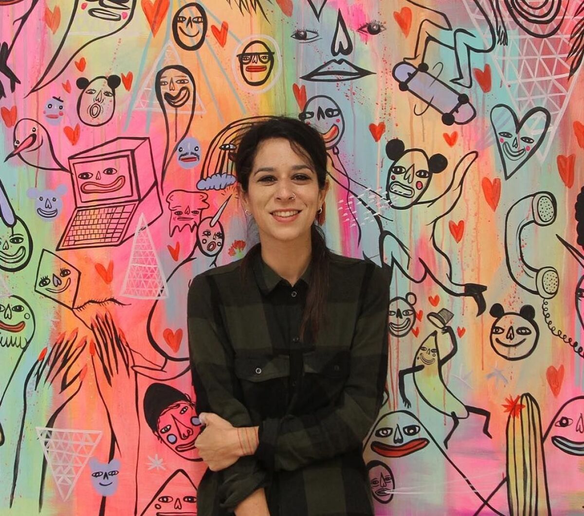 Artist Panca poses in front of her colorful mural for the New Children's Museum