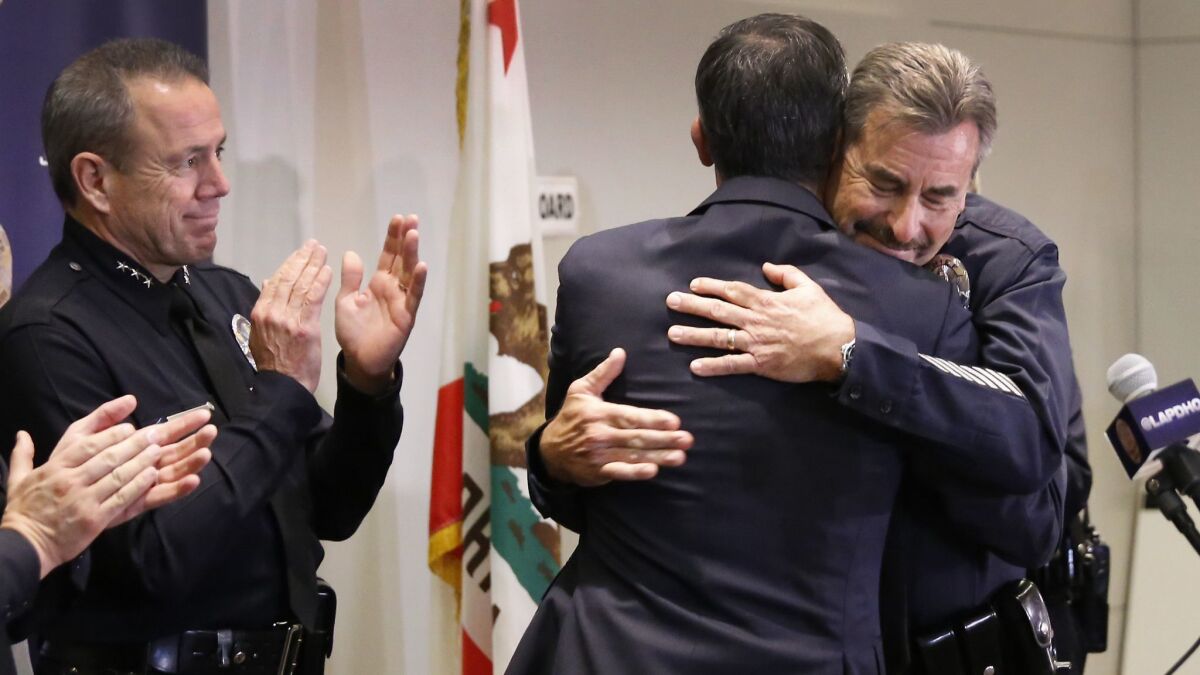 Beck and Mayor Eric Garcetti hug Jan. 19 after the chief announces his retirement. Michel Moore, left, who was later chosen to succeed Beck, applauds.
