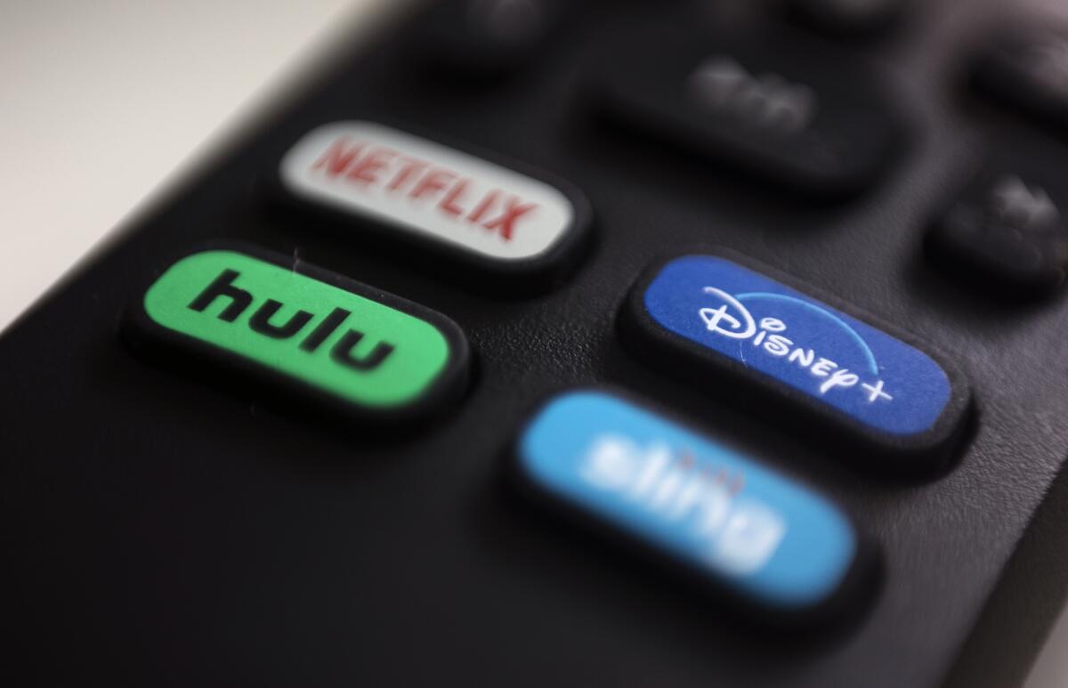 The logos for Netflix, Hulu, Disney+ and Sling TV are pictured on a remote control.