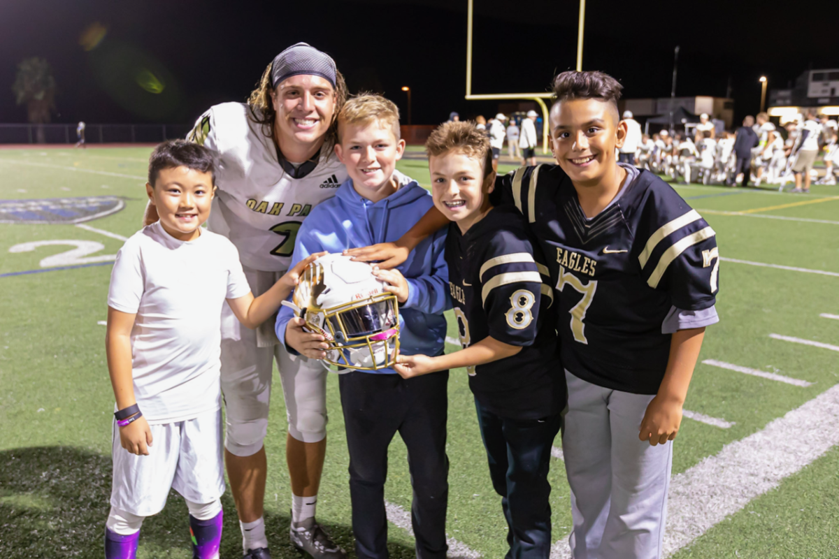 Oak Park quarterback/kicker Gianni Smith poses for a picture with some of his fans.