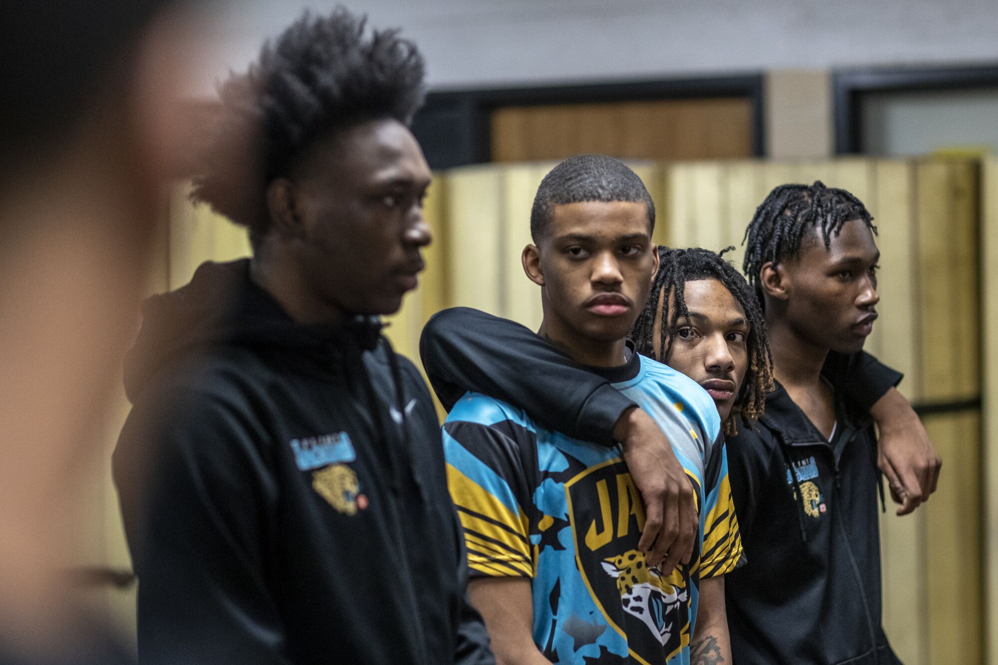 Flint basketball players D'Angelo Mays, Dakobe Lemon, Taevion Rushing and Maleek Sadler stand in the locker room.