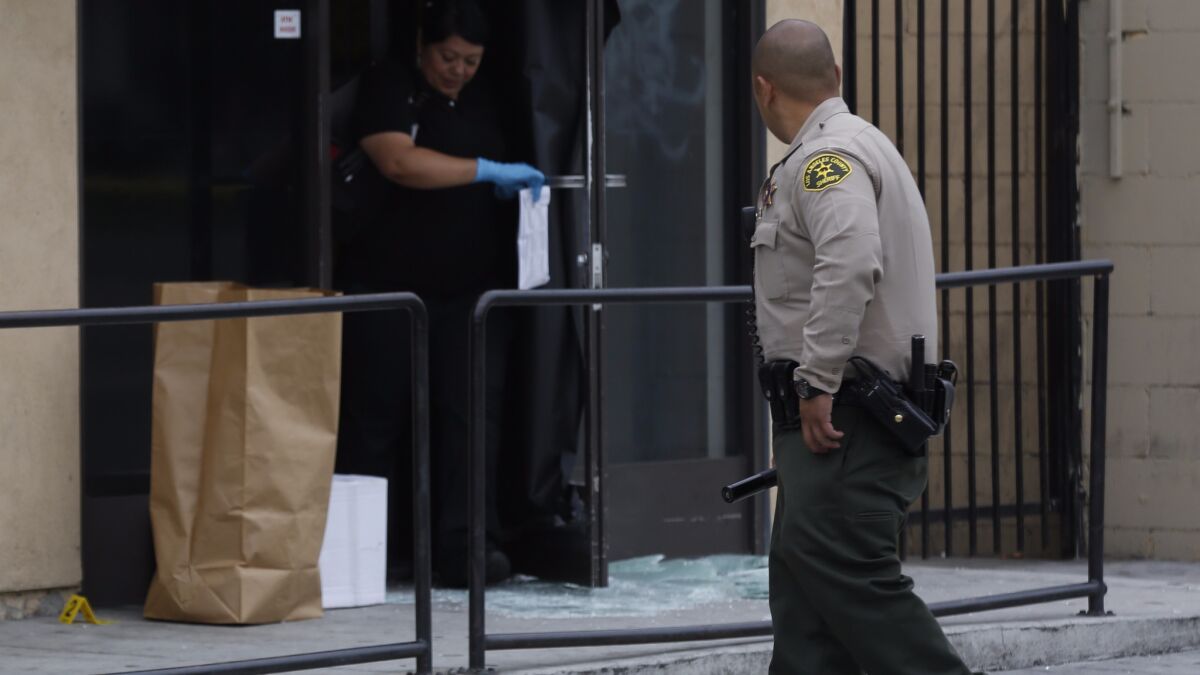Members of the Los Angeles County Sheriff's Department collect evidence at a marijuana dispensary in Walnut Park in June. The shop's owner shot and wounded two men trying to rob the store, authorities said.
