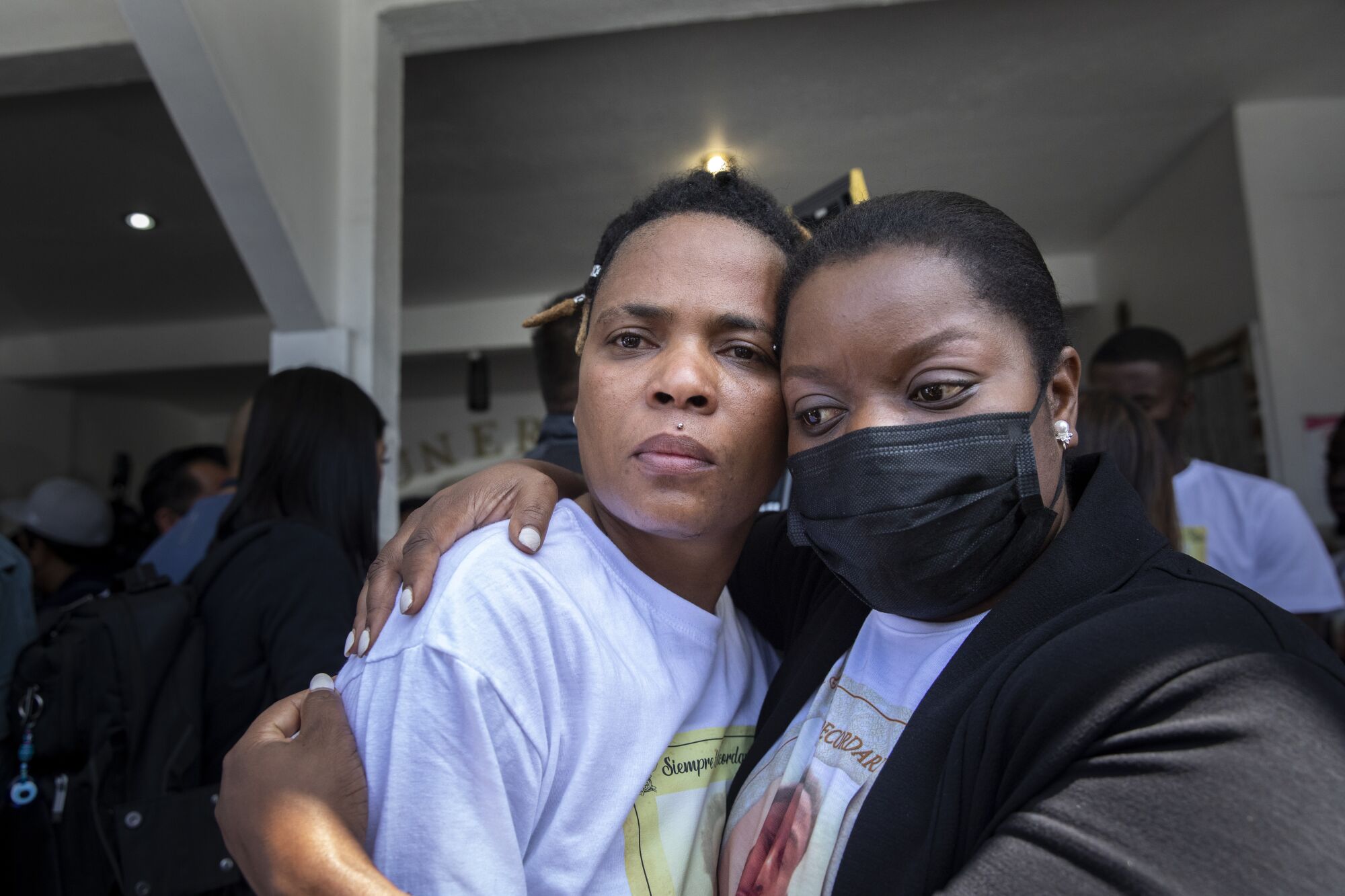 Pethou Archange, left, and Guerline Jozef, co-founder of Haitian Bridge Alliance, hug after the funeral.