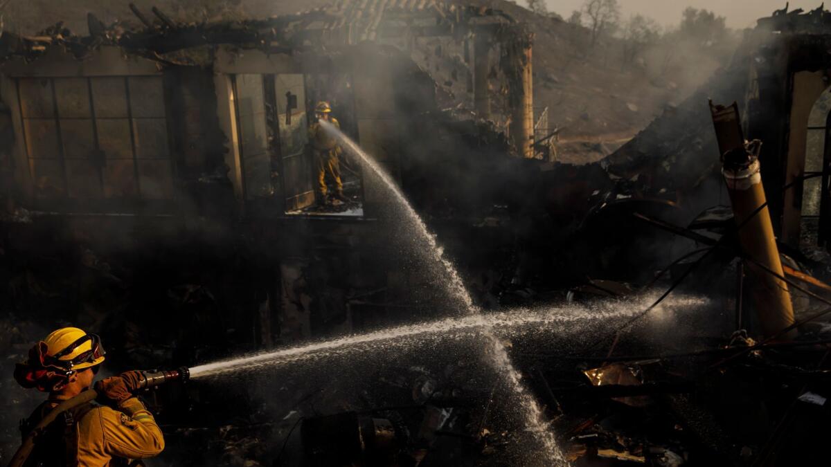 Humboldt County firefighters Lonnie Risling, left, and Jimmy McHaffie spray down smoldering fire beneath the rubble of a home that was destroyed by the Thomas fire in Montecito on Sunday.