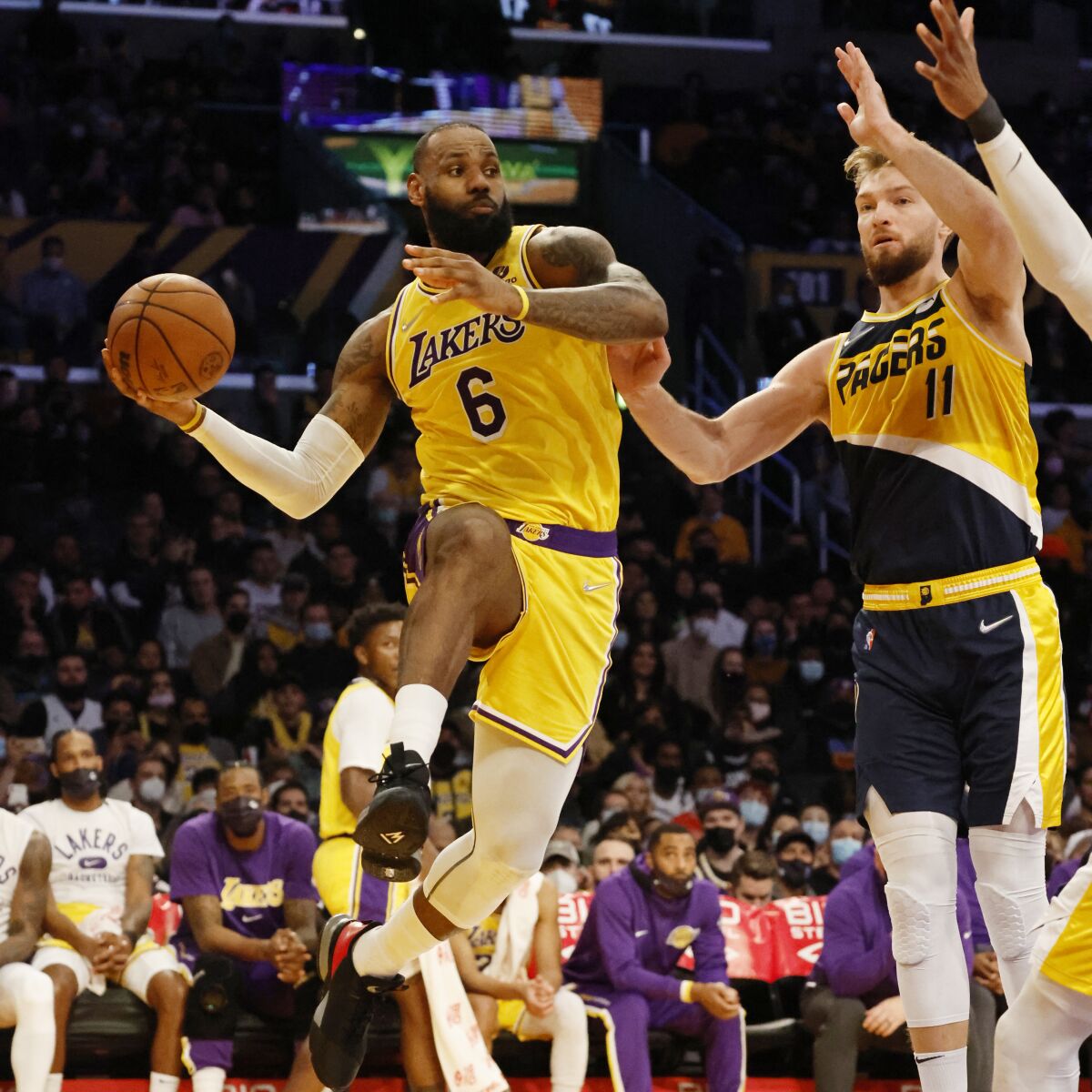 Lakers forward LeBron James leaps on the baseline to pass against Indiana Pacers forward Domantas Sabonis.
