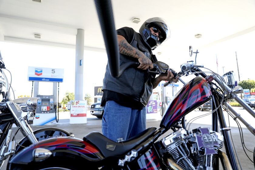 ORANGE, CA - MARCH 08: Mike Delgado, of Orange, pumps gas into his 2007 Swift 124 motorcycle at the Chevron gas station along Katella Ave. and Glassell on Tuesday, March 8, 2022 in Orange, CA. Delgado paid $13.04 for 2.196 gallons of premium gasoline. The average price of a gallon of self-serve regular gasoline in Los Angeles County rose 8.9 cents today, its 30th record in 32 days. In Orange County average price rose 8.8 cents, its 29th record in 34 days. (Gary Coronado / Los Angeles Times)