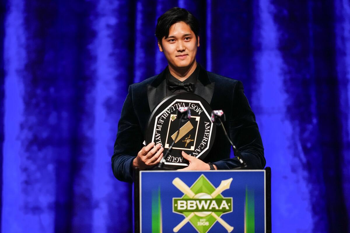 Shohei Ohtani wears a tuxedo and holds his award at a lectern.