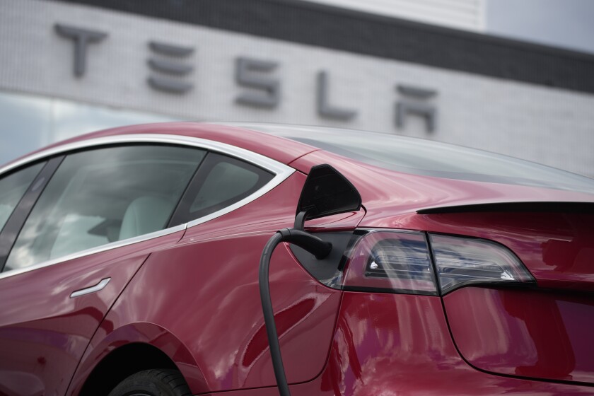 FILE - A 2021 Model 3 sedan charges at a Tesla dealership in Littleton, Colo., on June 27, 2021. On Sunday, Jan. 2, 2022, Tesla said the company delivered a record 936,000 vehicles the year before, up 87% from its 2020 delivery count. (AP Photo/David Zalubowski, File)