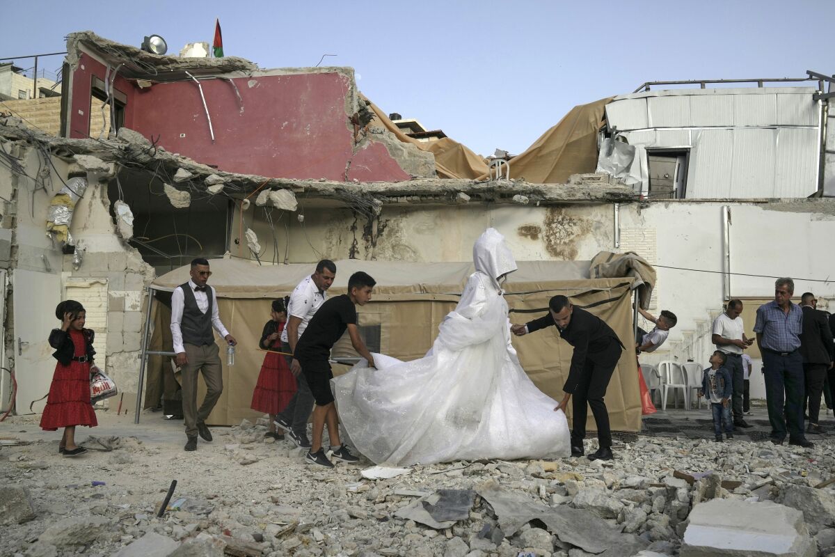 Palestinian bride Rabiha al-Rajby and groom Mohyeldin Nasrallah start their wedding ceremony from the ruins of al-Rajby's home in the east Jerusalem neighborhood of Silwan, Saturday, June 11, 2022. Israeli authorities demolished the building, displacing its 35 residents, last month, saying it was built without municipal permit as part of the wider struggle between the city and Palestinian residents. (AP Photo/Mahmoud Illean)